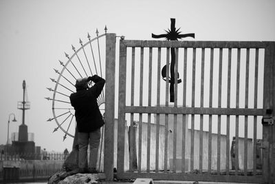 Man photographing cross while standing by gate