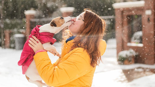 Portrait of young woman with dog on snow