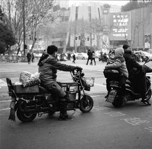 People riding motorcycle on road in city