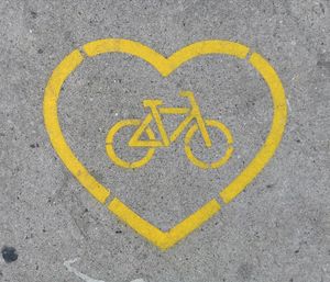 Directly above shot of yellow heart shape with bicycle lane marking on road