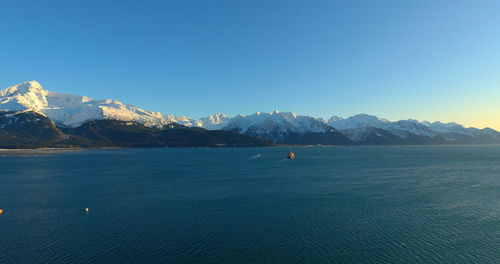 Scenic view of sea and mountains against clear blue sky