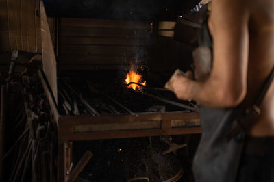 Blacksmith stoking the fire in the forge of his workshop.	
