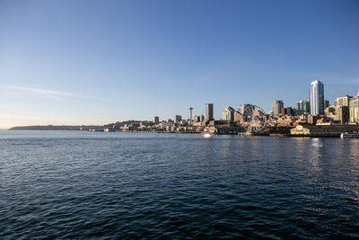 Sea by buildings against clear blue sky