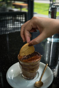 Midsection of person holding ice cream on table