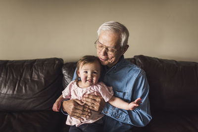 Portrait of grandfather holding toddler and looking at her