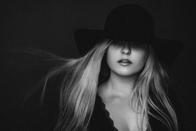 Portrait of young woman against black background