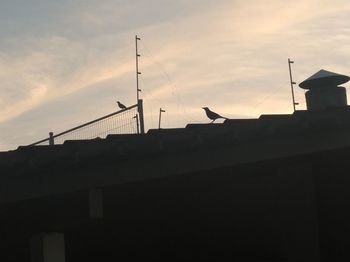 Low angle view of silhouette roof against sky