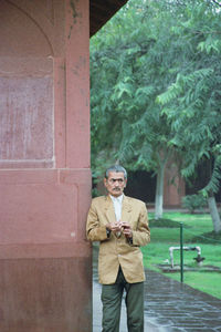 Senior man looking away while leaning on wall