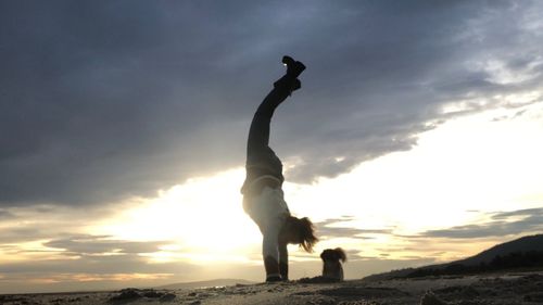 Silhouette man standing on rock against sky during sunset