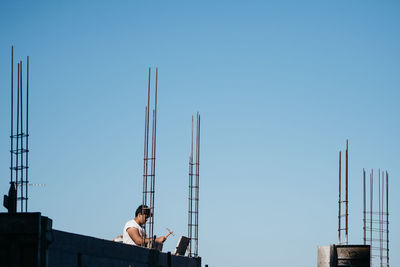 Low angle view of cranes against clear blue sky