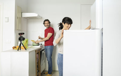 Full length portrait of young couple standing against wall