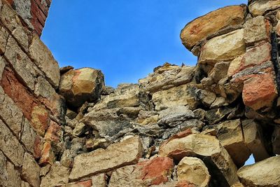 Low angle view of stone wall against blue sky