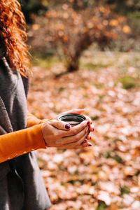 Midsection of woman holding autumn leaf