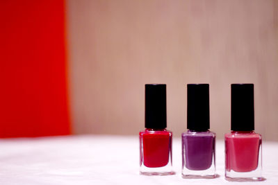 Close-up of nail polish bottles on table against wall