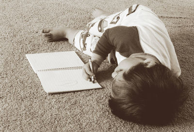 High angle view of man playing with cat resting on floor