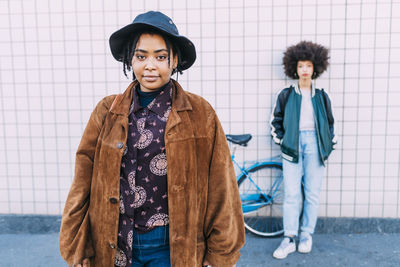 Woman wearing hat and overcoat standing with friend in background