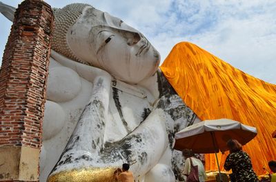 Rear view of people visiting reclining buddha against sky