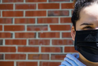 Close-up portrait of a teenage girl against brick wall