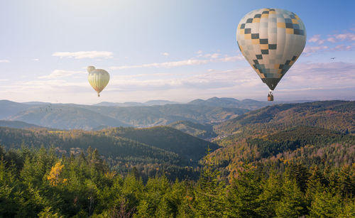 Hot air balloon flying over mountains against sky