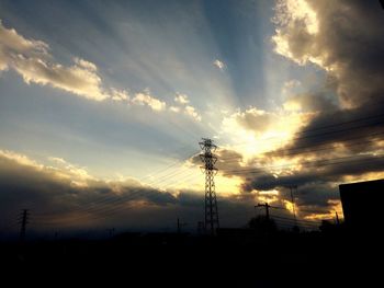 Low angle view of electricity pylon against cloudy sky