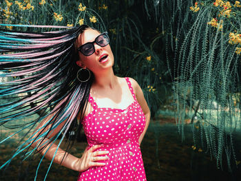 Portrait of woman tossing hair against tree