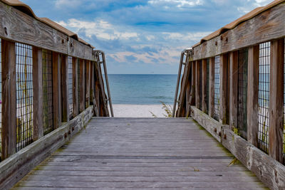 Boardwalk leading towards sea against sky