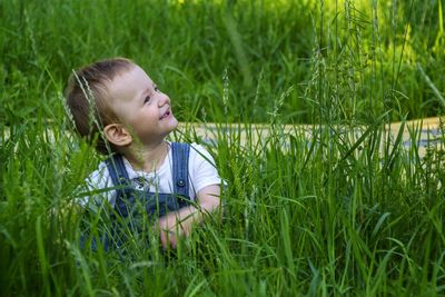 Smiling cute boy sitting on grassy field