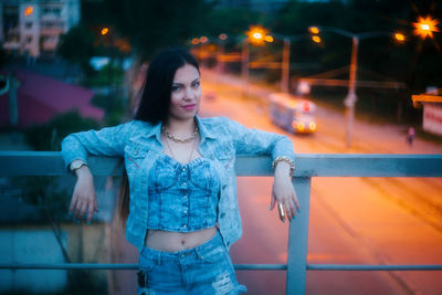 Portrait of smiling young woman standing in city at night