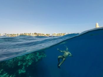 Man swimming in sea against clear blue sky