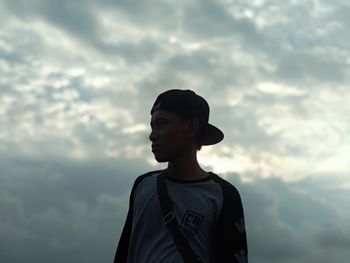 Portrait of young man looking away against sky