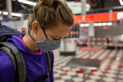 Female traveler with nose and mouth covering mask to comply with covid-19 regulations in airport.