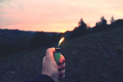 Close-up of cropped hand holding fire