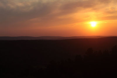 Scenic view of silhouette landscape against orange sky