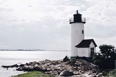 Lighthouse by sea against sky