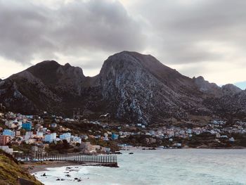 Scenic view of townscape by mountains against sky