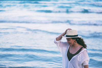 Woman wearing hat standing by sea