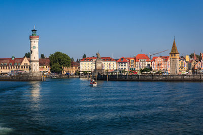 View of buildings by sea against blue sky