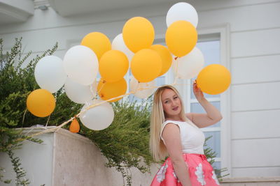 Portrait of a smiling young woman holding balloons