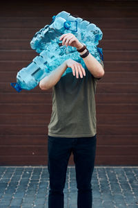 Young man throwing out empty used plastic water bottles into trash bin. collecting plastic waste