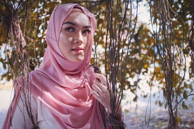 Young woman wearing hijab by branch