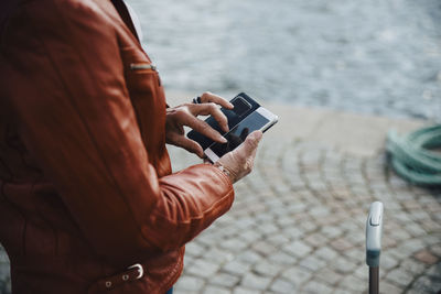 Midsection of senior woman using mobile phone on sidewalk