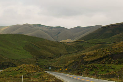 Scenic view of street by mountains against sky