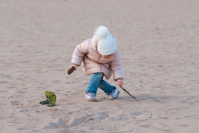 Little girl is playing on an empty beach on a cold day