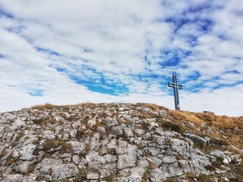 Low angle view of cross on rock against sky