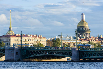 Bridge over river in city against cloudy sky