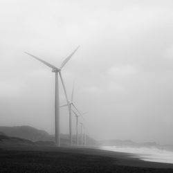 Wind turbines on field against sky