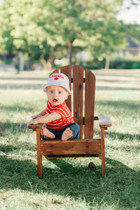 Portrait of boy sitting on bench in park