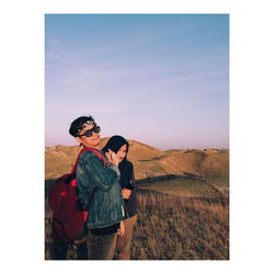 Couple standing on mountain against sky