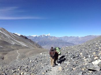 People standing on mountain against blue sky