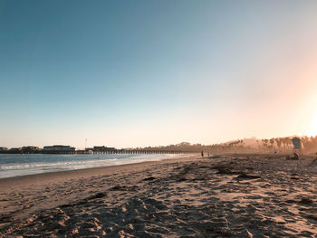 Scenic view of beach against clear sky during sunset